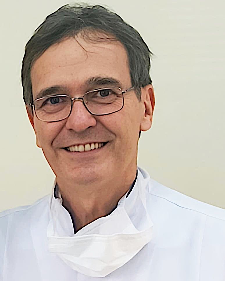 Dr. Fábio de Souza Telles, de jaleco, sorrindo no consultório
